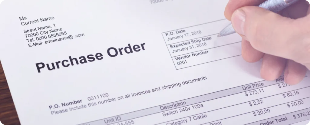 Purchase order document being held, showing vendor details, P.O. date January 17 2018, and line items with pricing